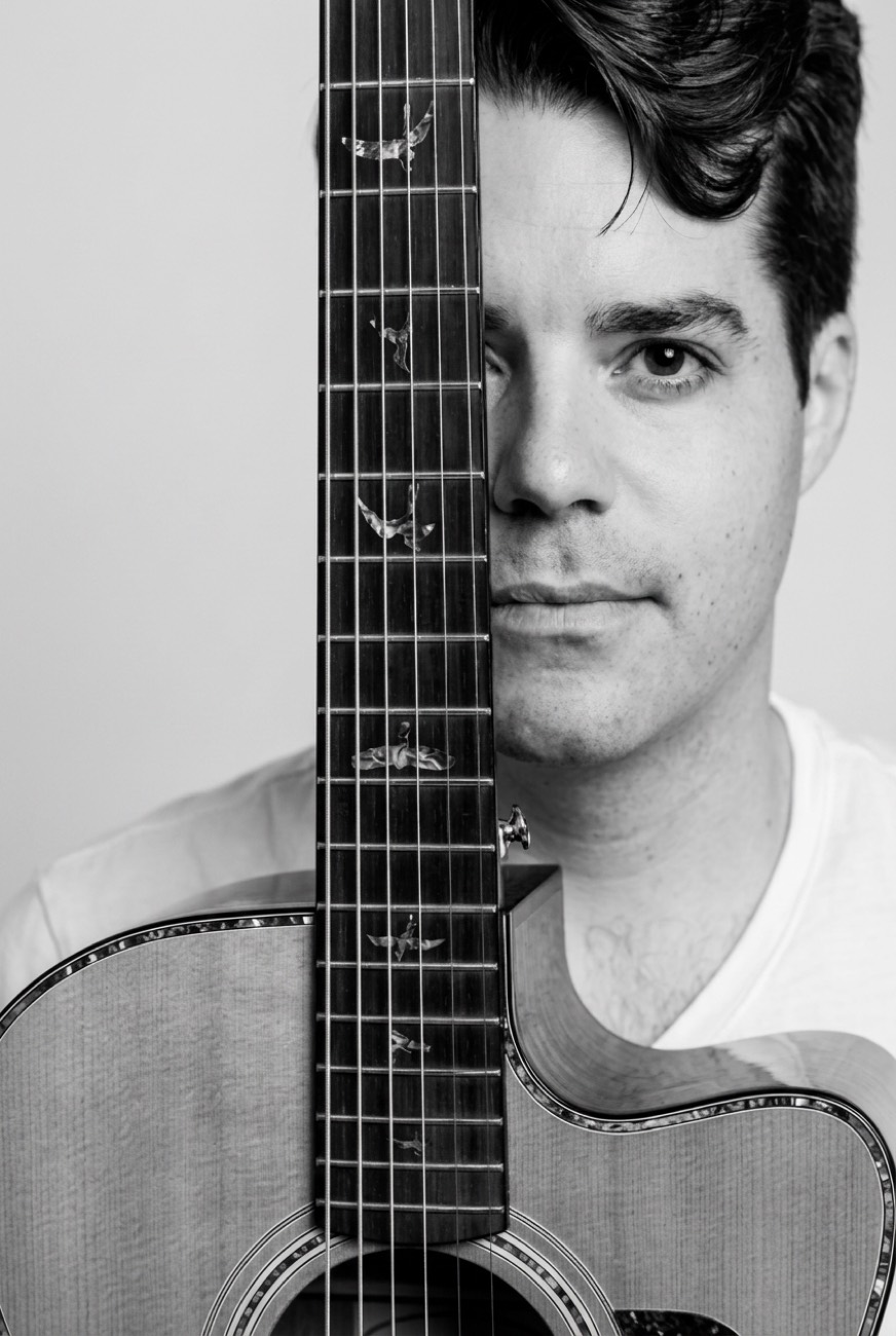 Stevie Matthews, online guitar teacher, holding an acoustic guitar